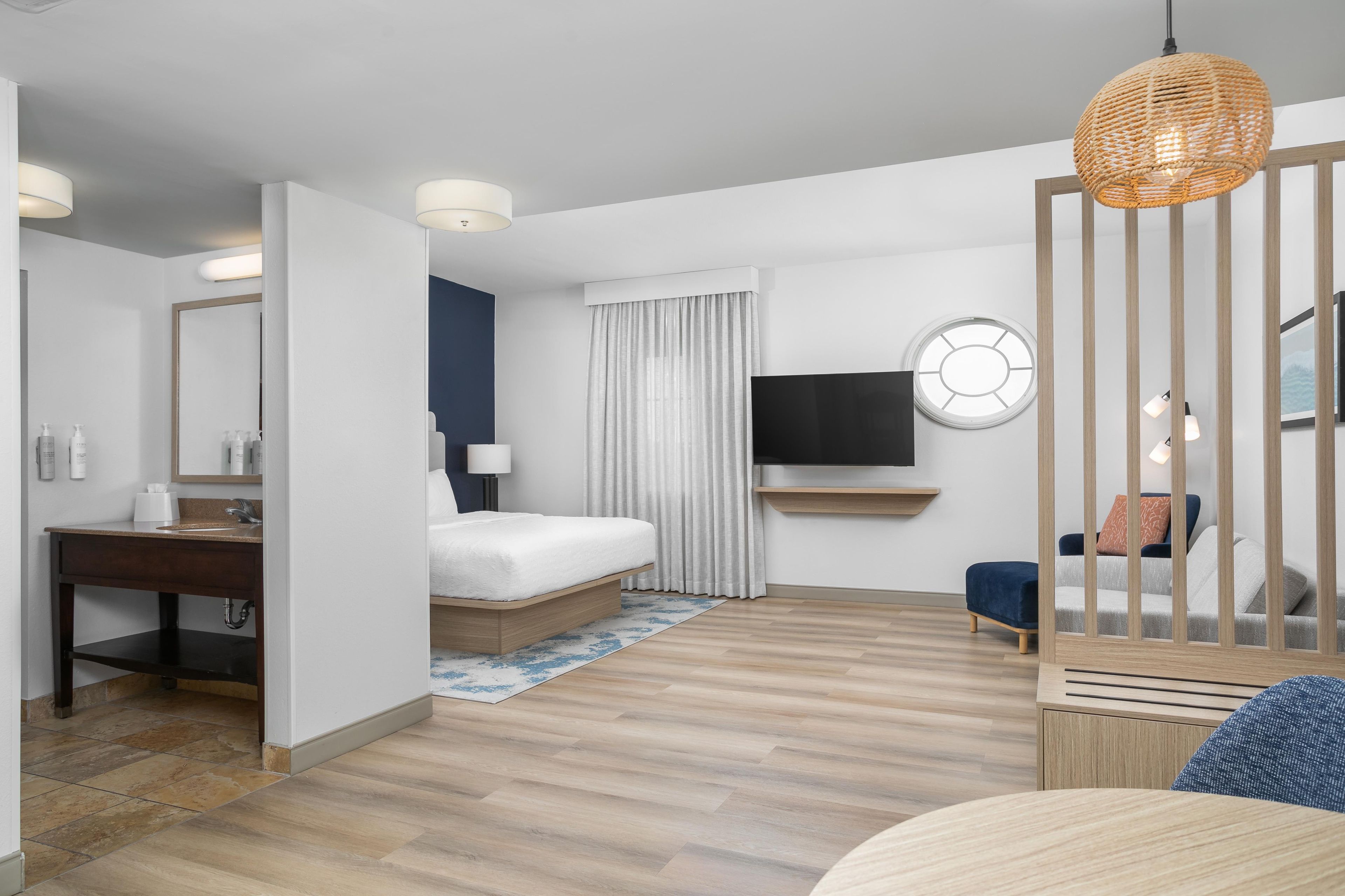 Ein Hotelzimmer mit Bett, Schreibtisch, Fernseher und Blick ins Freie.