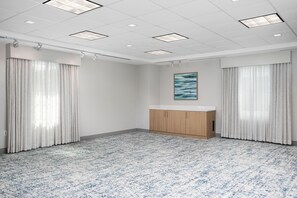 A room with a patterned carpet, white walls, a wooden cabinet, and a painting on the wall. - Hampton Inn New Smyrna Beach (New Smyrna Beach)