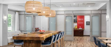 A modern conference room with a wooden table, blue chairs, and a red waffle sign.