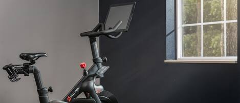 A stationary bike with a digital display, a seat, handlebars, and pedals.