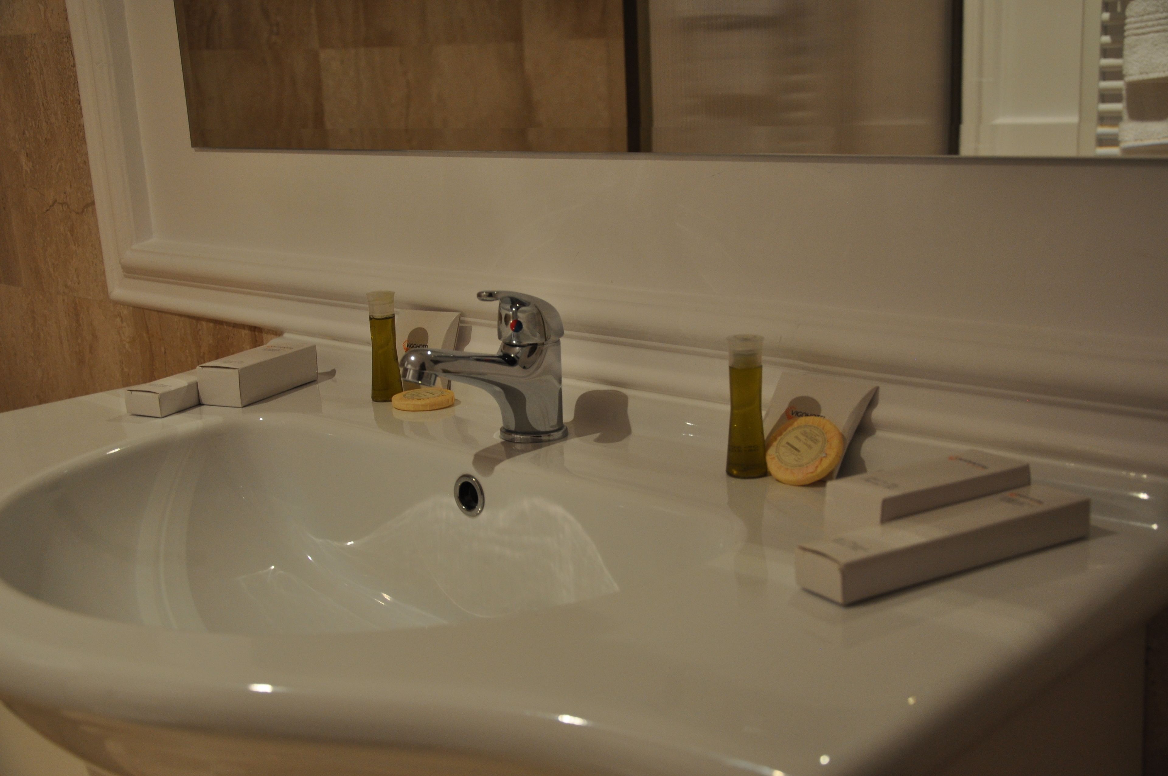 A bathroom sink with a mirror above it, a faucet, and toiletries on the counter.