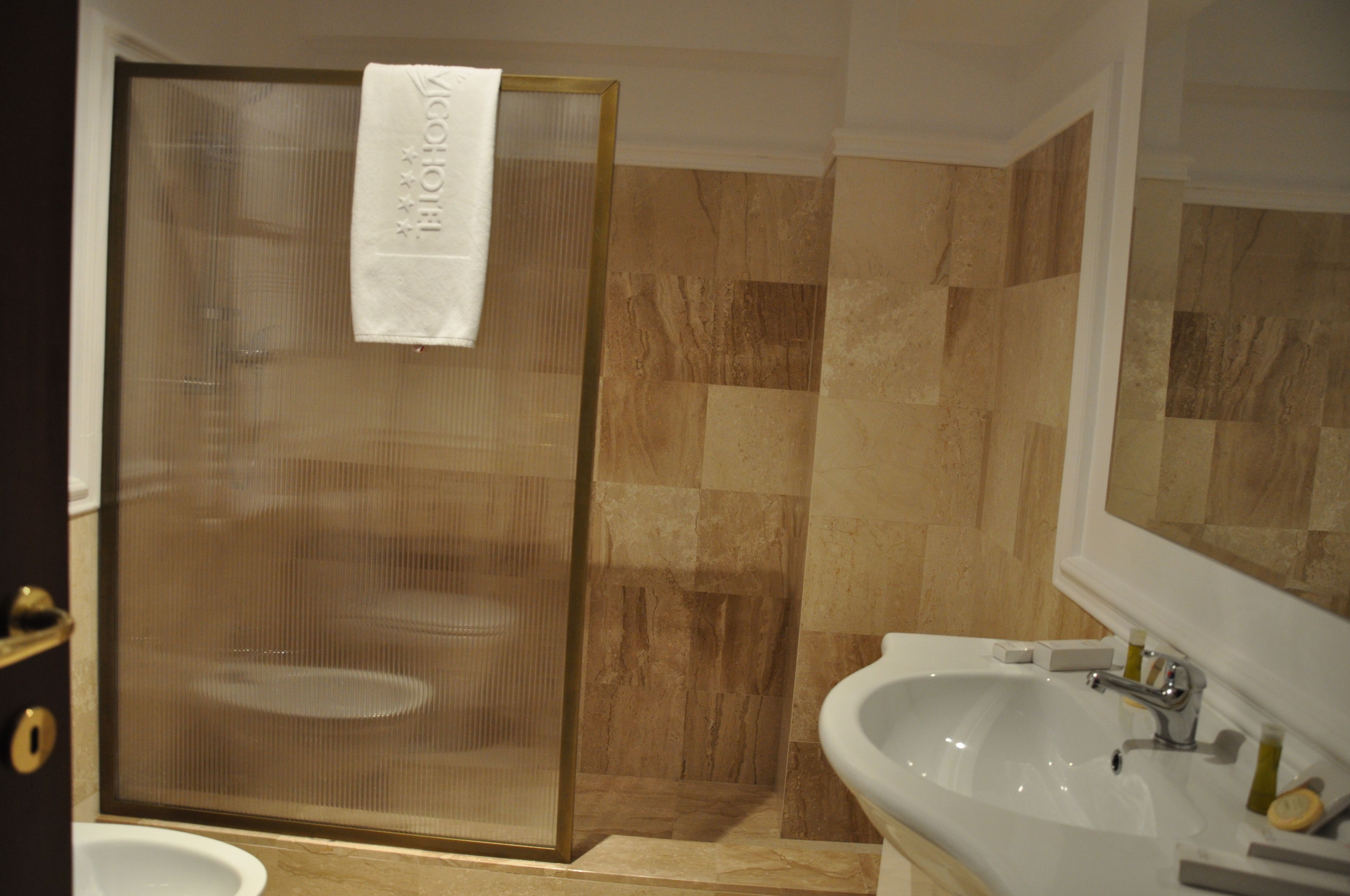 A bathroom with a shower enclosure, a sink, and a mirror.