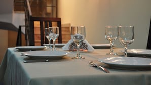 A dining table set with plates, cutlery, and wine glasses, indicating a formal dining arrangement.