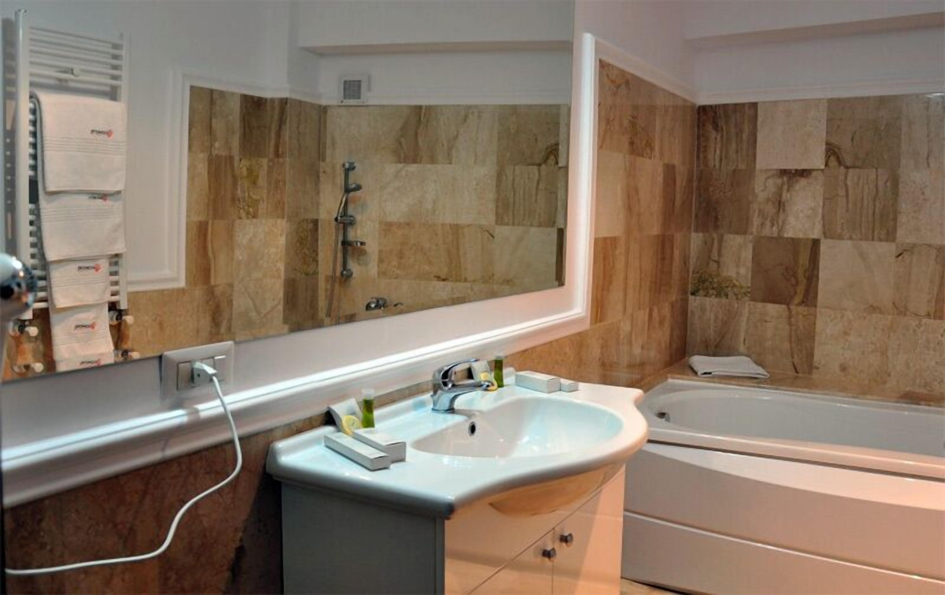 A bathroom with a white sink, a bathtub, and a mirror.