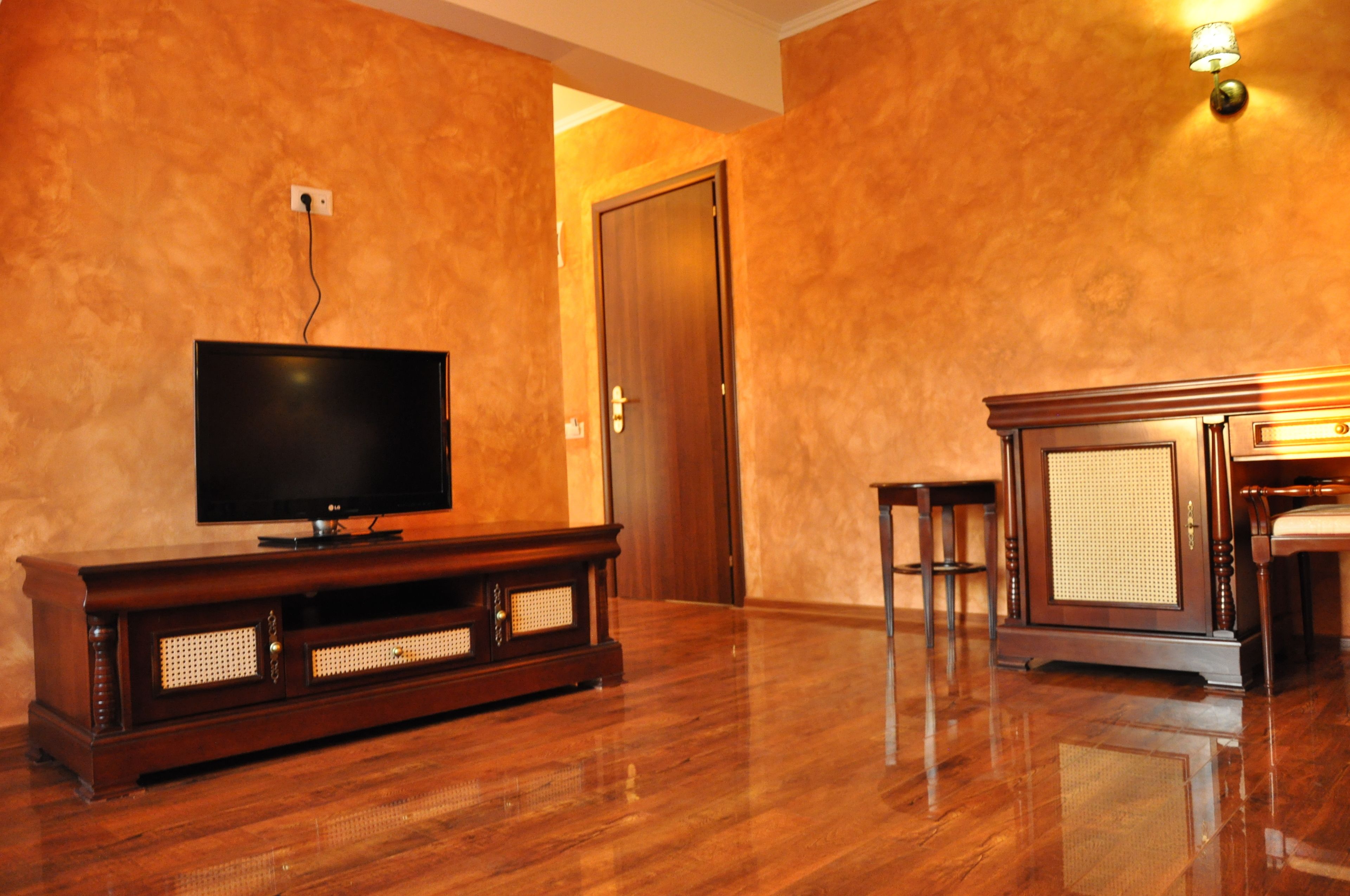 A room with a wooden entertainment center, a flat-screen TV, and a cabinet with a woven front.