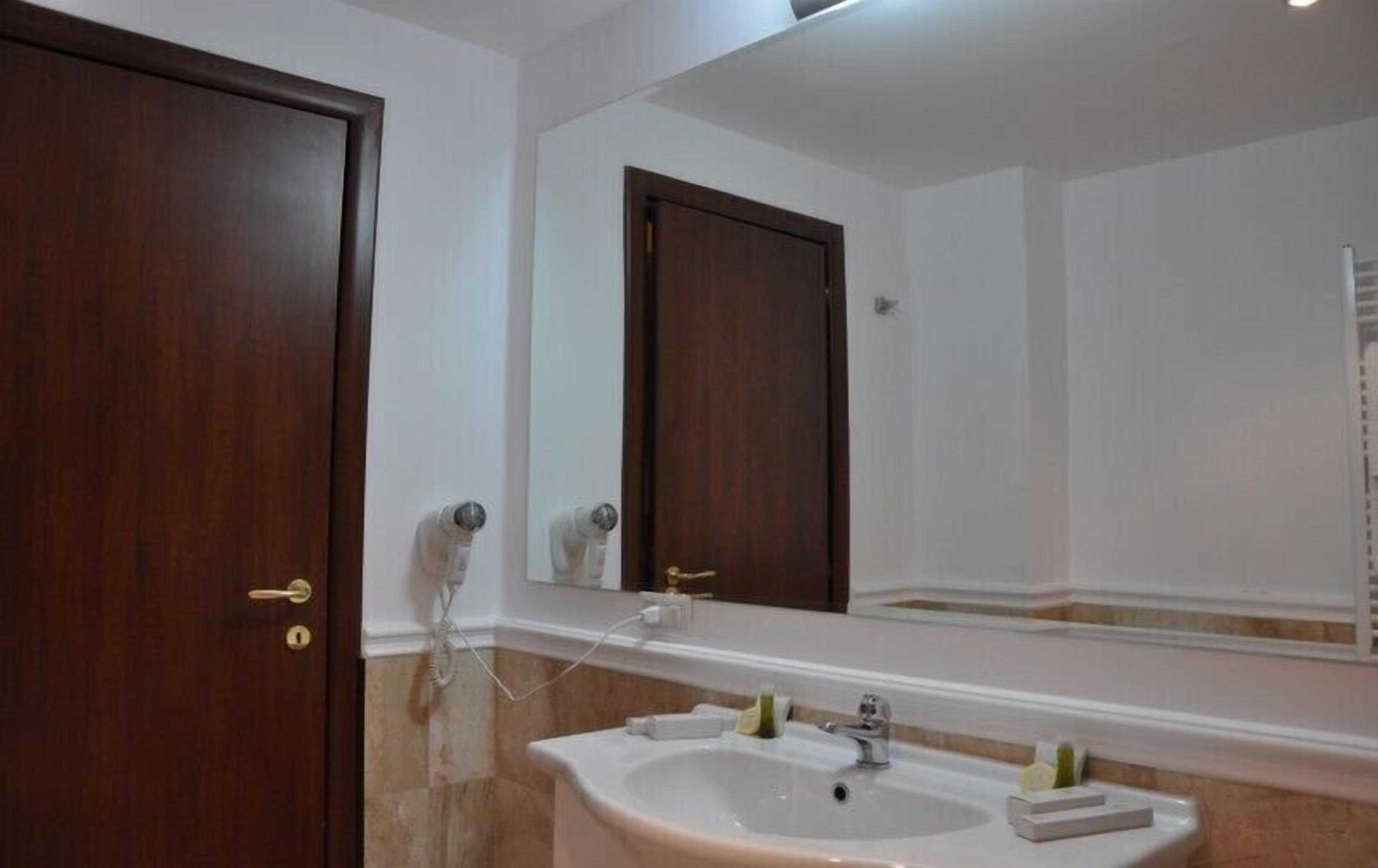 Une salle de bain avec un lavabo, un miroir et deux portes en bois.