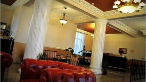 A lobby with marble columns, a red leather sofa, and a chandelier.