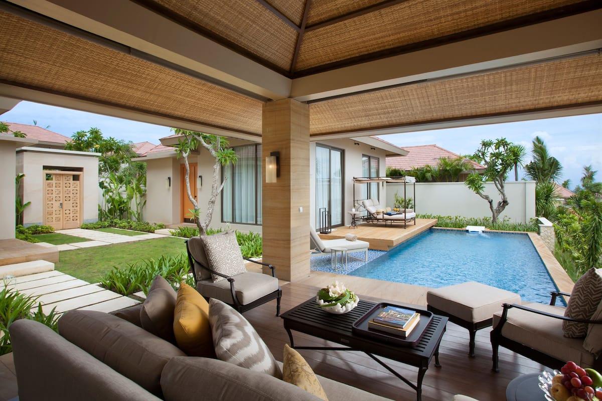 A modern outdoor living area with a pool, comfortable seating, and a view of the surrounding landscape.
