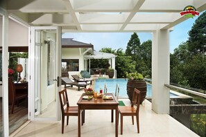 A modern outdoor dining area with a pool, wooden furniture, and a view of the pool and greenery. - Madagui Forest City (Da Huoai)