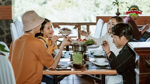 Un grupo de personas cenando en un restaurante con una olla caliente compartida.