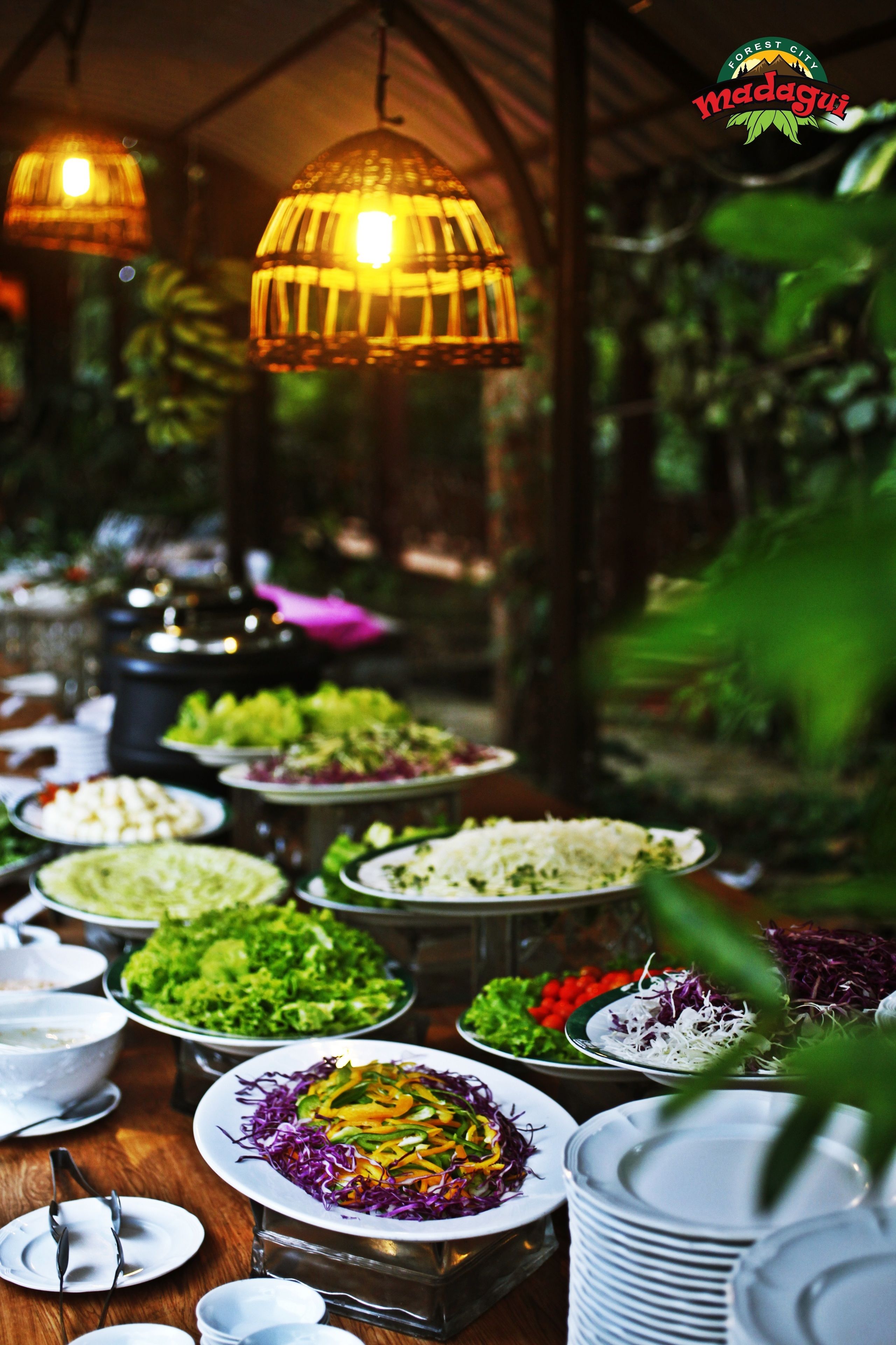 Una mesa de buffet con diversos platos y una estructura cubierta con luces colgantes.