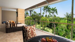 A balcony with a view of palm trees and a dining table with fruits.