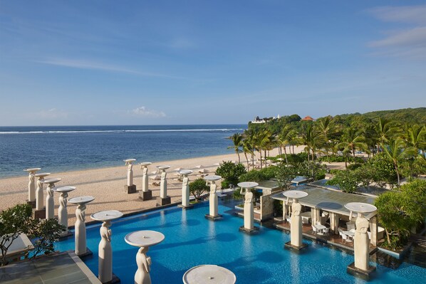 A resort pool with multiple seating areas and a view of the beach. - The Mulia Bali (Nusa Dua)