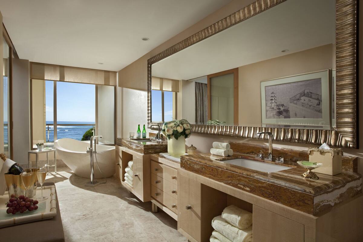 A luxurious bathroom with a large bathtub, a double sink vanity, and a large mirror.