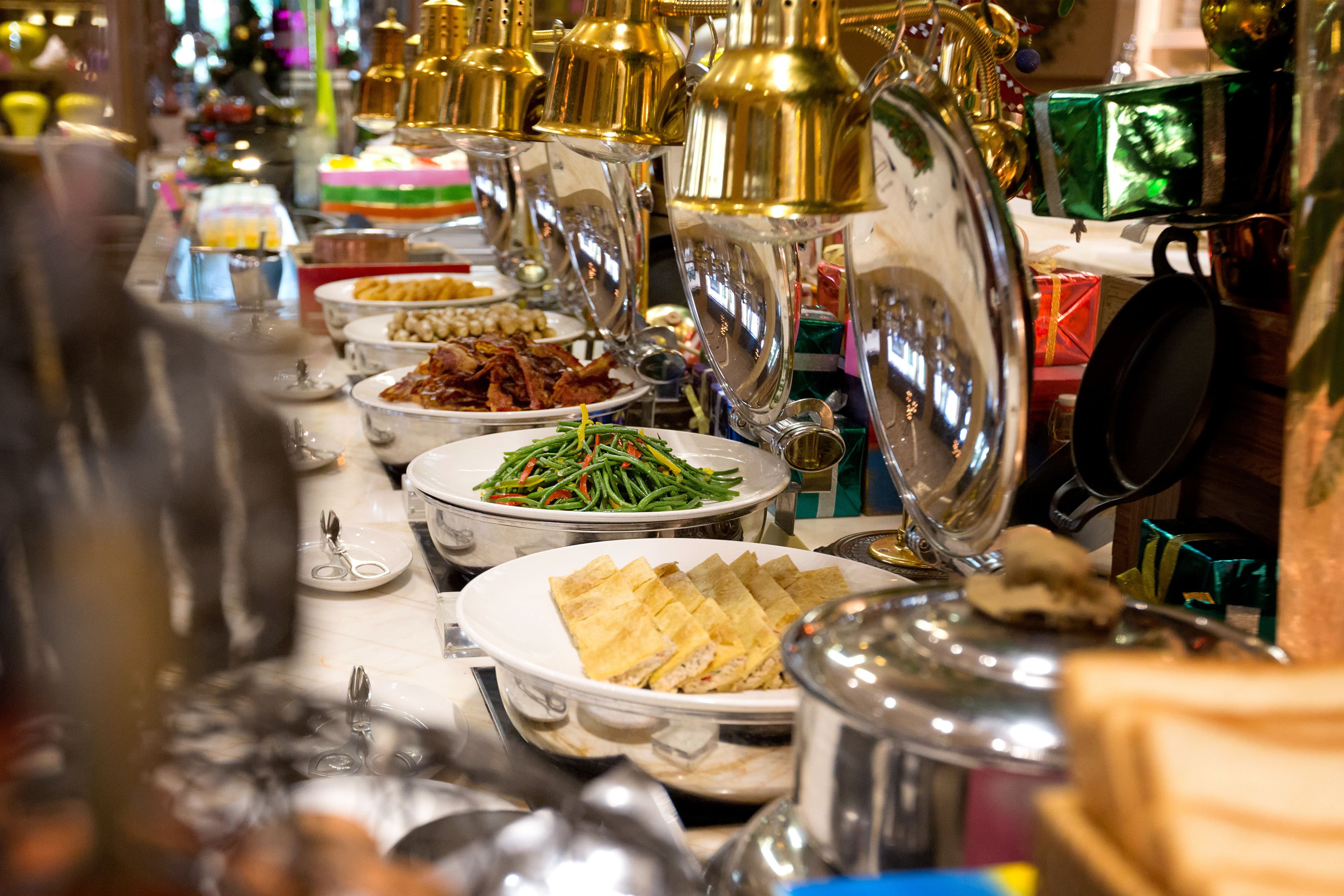 A buffet with various dishes and a variety of utensils.