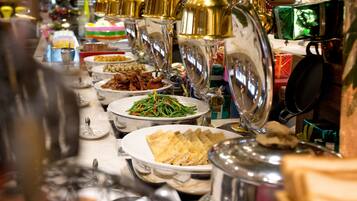 A buffet with various dishes and a variety of utensils.