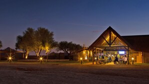 A building with a covered outdoor area, possibly a bar or restaurant, with tables and chairs. - Desert Camp (Sesriem)
