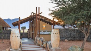 A desert-themed entrance with a wooden archway, a sign reading "Desert Camp," and large decorative stones. - Desert Camp (Sesriem)