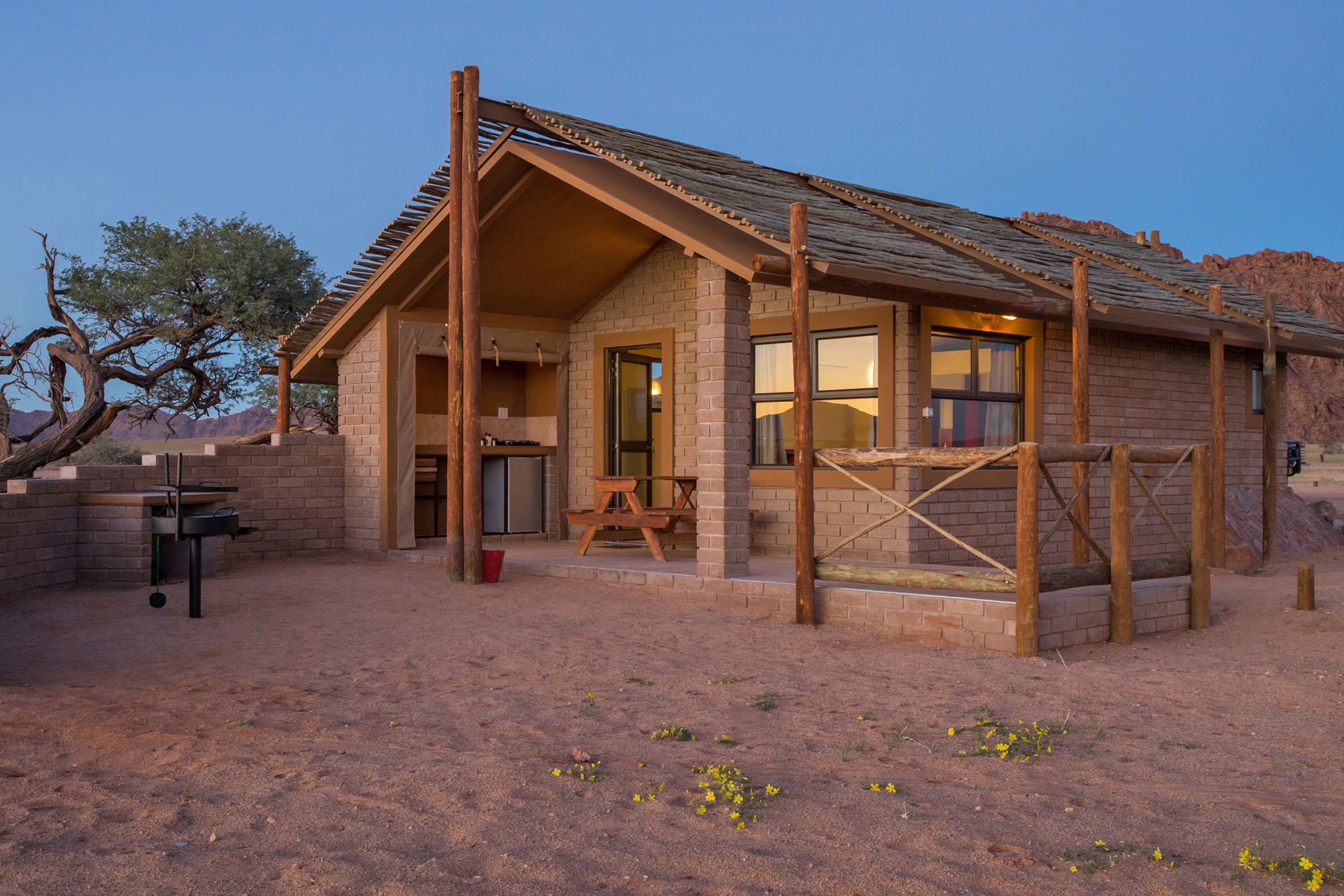 A rustic cabin with a wooden deck, a picnic table, and a brick exterior.