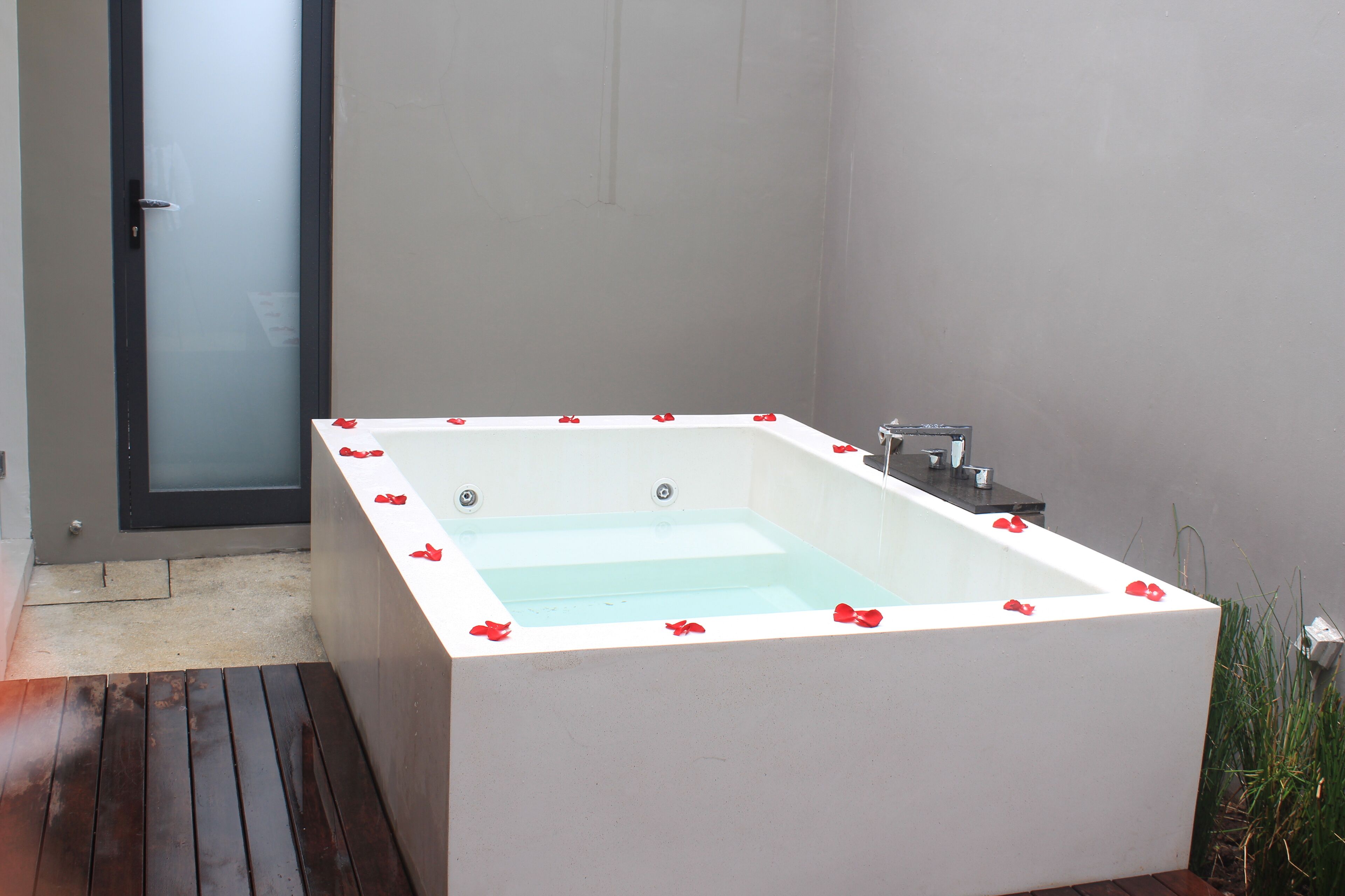 A rectangular bathtub with a white interior, surrounded by a wooden deck.