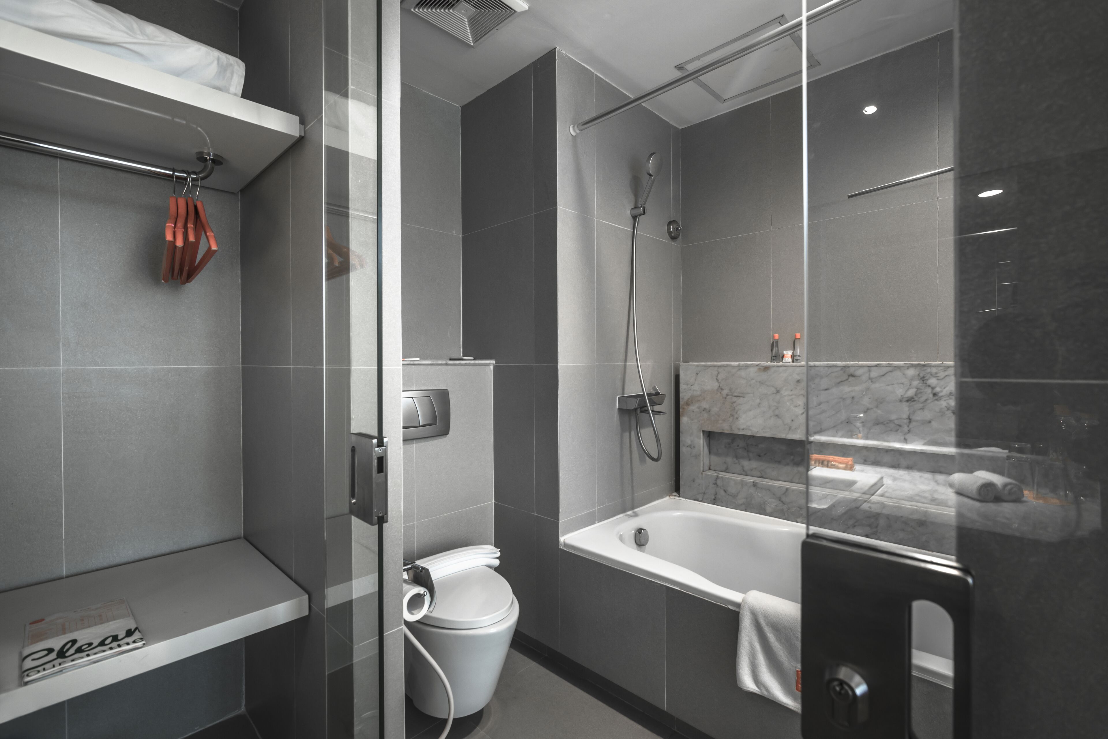 A modern bathroom with a glass shower enclosure, a white bathtub, and a toilet.