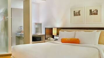 A hotel room with a bed, a nightstand, a lamp, a mirror, and a picture of a city scene on the wall.