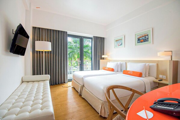 A hotel room with two beds, a sofa, a desk with a telephone, and a balcony with curtains. - HARRIS Hotel & Conventions Malang  (Malang)