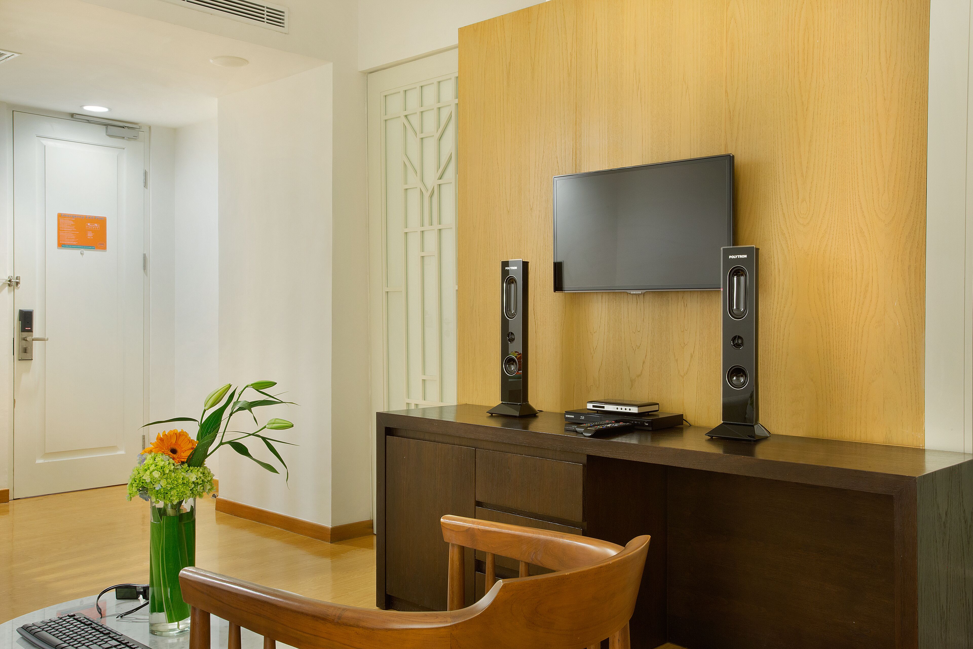 Een receptiebalie met een flatscreen televisie, twee speakers en een bloemenvaas.