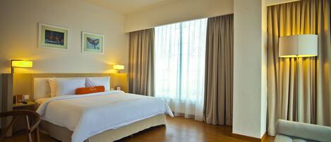 Une chambre d’hôtel avec un grand lit, un canapé, un bureau et une lampe.