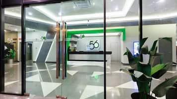 A modern reception area with glass doors, a green accent wall, and a reception desk labeled '56'.