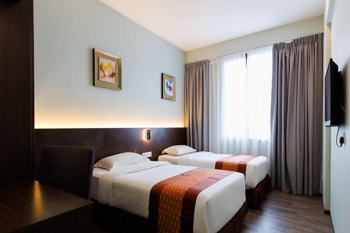 Habitación de hotel con dos camas, un escritorio, una silla y un televisor.