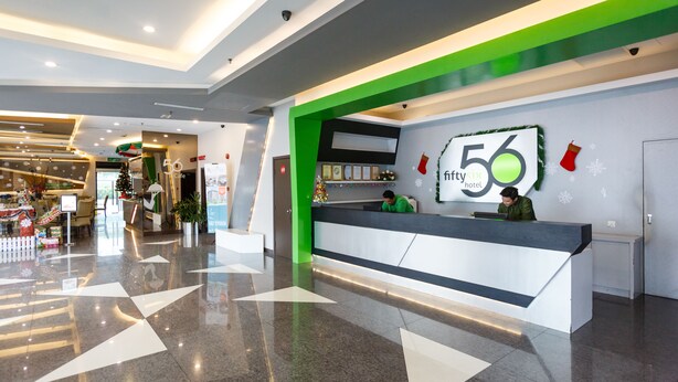 A hotel reception area with a modern design, including a reception desk, a Christmas tree, and a sign indicating the hotel name and number. - 56 Hotel (Kuching)