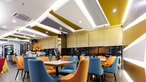 A modern dining area with blue and orange chairs, a central table, and a decorative plant. - 56 Hotel (Kuching)