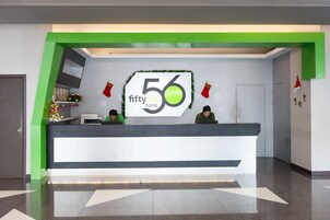 Una mesa de recepción con un letrero que dice "FiftySix Hotel" y dos empleados sentados detrás.
