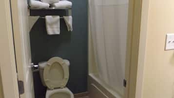 Un baño pequeño con inodoro, un estante con toallas y cortina de ducha.