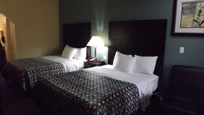 A hotel room with two beds, a nightstand with a lamp, a chair, and a framed picture on the wall. - SUNRISER INN (Kilgore)