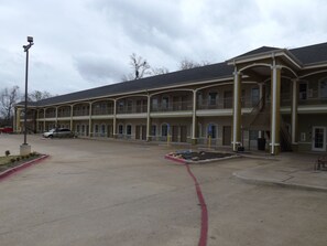 A motel with a central courtyard, multiple balconies, and a parking area.