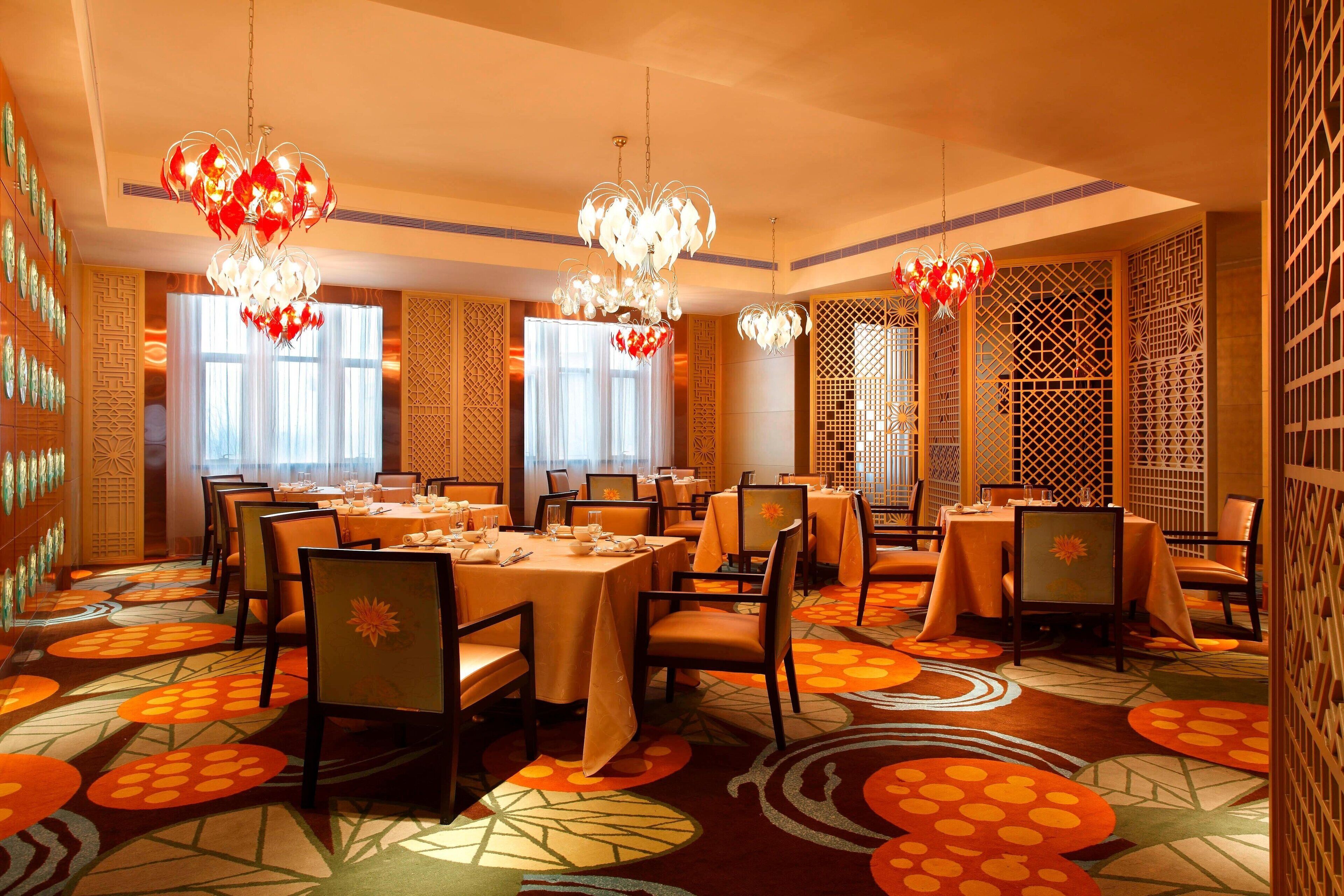 A dining area with multiple tables, chairs, and decorative lighting fixtures.