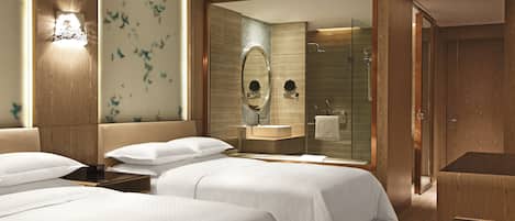 A hotel room with two beds, a bathroom with a glass shower, and a wooden wardrobe.