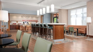 A modern hotel lobby with a bar area, seating, and a kitchen in the background. - Hampton Inn Cleveland, TN (Cleveland)