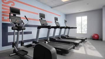 A gym with treadmills, ellipticals, and a red exercise ball.