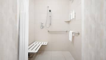 A modern bathroom with a shower, grab bar, and a bench.