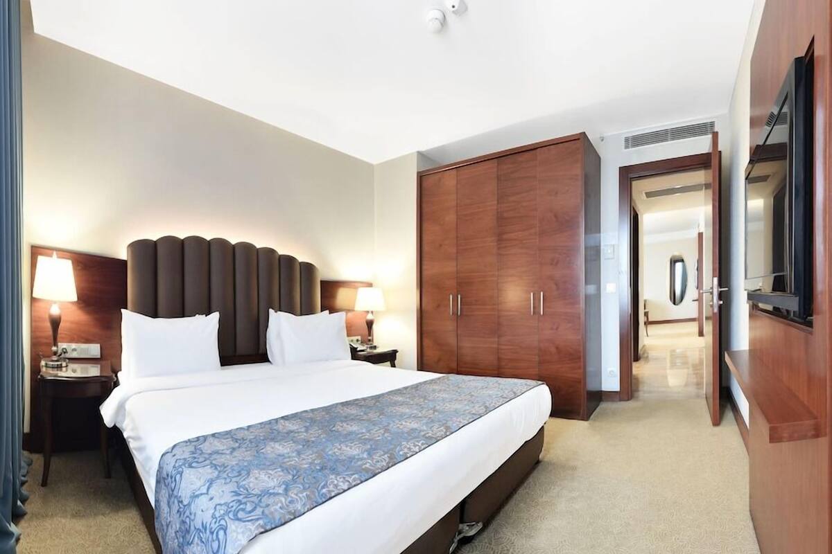 A hotel room with a large bed, wooden wardrobe, and a television.