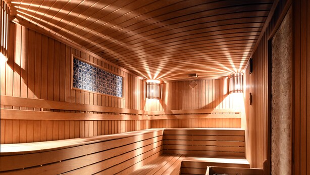 Un sauna avec des bancs en bois et un mur recouvert de carreaux.