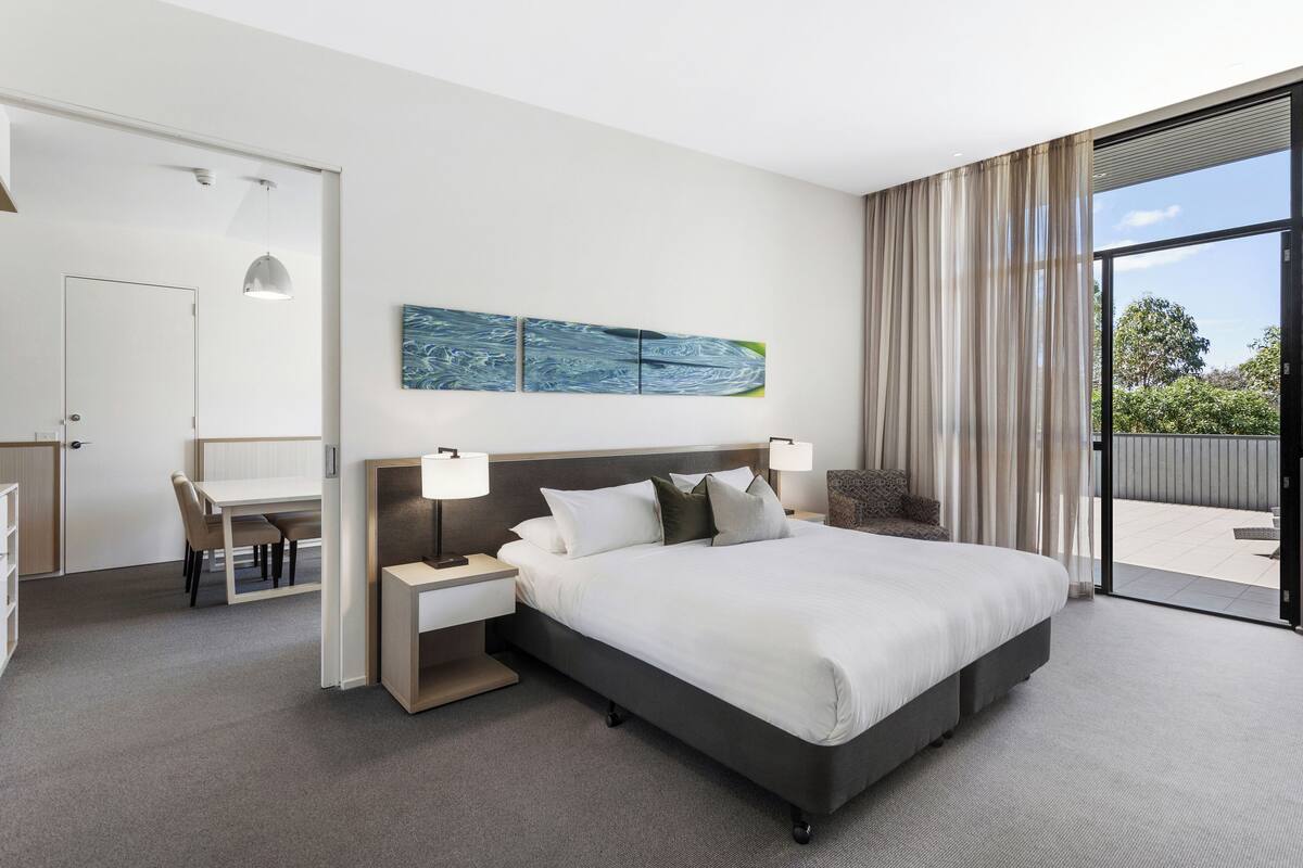Une chambre d’hôtel moderne, dotée d’un grand lit, d’un bureau et offrant une vue sur l’extérieur.