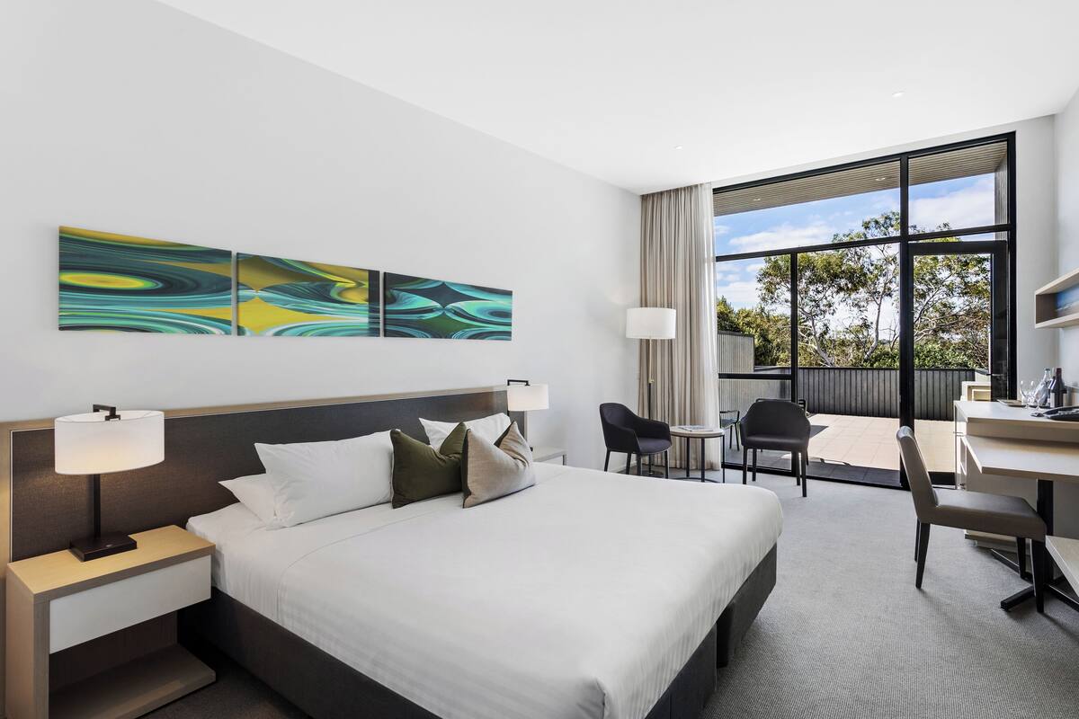 Une chambre d’hôtel moderne avec un grand lit, un bureau et une vue sur l’extérieur.