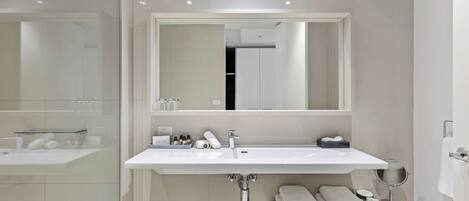A modern bathroom with a large mirror, a sink, and a shower area.