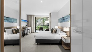 Une chambre d’hôtel moderne, dotée d’un grand lit, d’un bureau et offrant une vue sur l’extérieur.