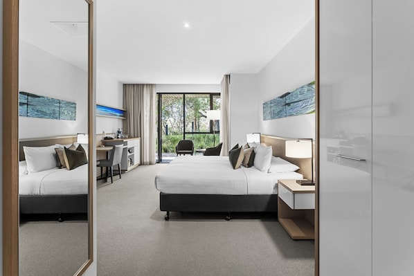 A modern hotel room with a large bed, a desk, and a view of the outdoors.