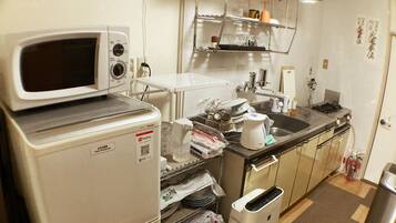 Una cocina compacta con microondas, tostadora, lavamanos y un refrigerador pequeño.